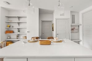 A modern kitchen with a central island, white cabinetry, and pendant lighting. - Relaxed 1BR Apartment Stay at The Nelson TNS 4204 (Austin)