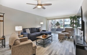 A modern living room with a sofa, armchairs, a coffee table, and a TV.