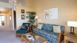 A living room with a sofa, armchair, coffee table, and a painting on the wall. - Ocean View 4BR, 2 Condos for 12 in Kihei! (Kihei)