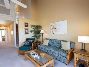 A living room with a sofa, armchair, coffee table, and a painting on the wall. - Ocean View 4BR, 2 Condos for 12 in Kihei! (Kihei)