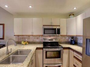 A modern kitchen with stainless steel appliances, a granite countertop, and a two-basin sink. - Kihei, Maui Kamaole, Spacious 4 BR, Ocean View, Sleeps 12 (Kihei)