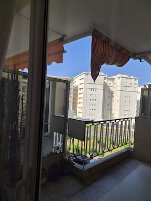 A balcony with a view of high-rise buildings, a railing, and a potted plant.