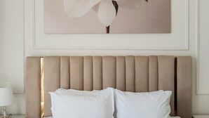 A neatly made bed with white linens and pillows, a beige upholstered headboard, and a large floral artwork above it. - Beautiful Dubai Marina View 1BR - Walk to Beach & Metro (Dubai)