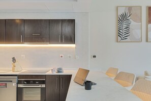 A modern kitchen with dark wood cabinets, a built-in oven, and a coffee machine. - Beautiful Dubai Marina View 1BR - Walk to Beach & Metro (Dubai)