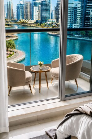 A modern hotel room with a balcony overlooking a marina and city skyline. - Beautiful Dubai Marina View 1BR - Walk to Beach & Metro (Dubai)