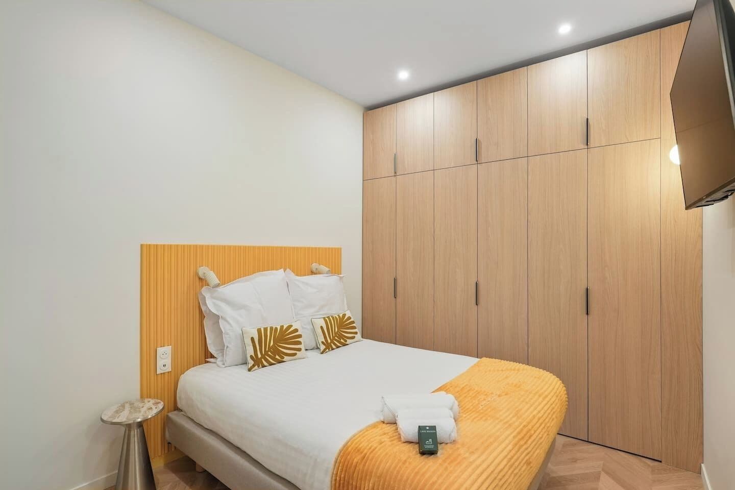 A hotel room with a bed, a bedside table, a wardrobe, and a television.