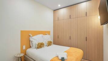 A hotel room with a bed, a bedside table, a wardrobe, and a television.