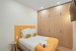 Ein Hotelzimmer mit einem Bett, einem Nachttisch, einem Kleiderschrank und einem Fernseher.