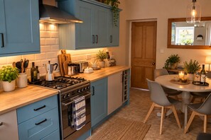 A kitchen with blue cabinets, a stove, and a dining area with a table and chairs.