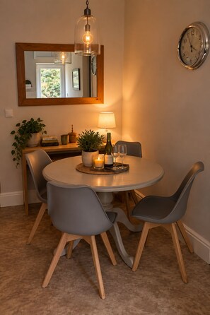 A dining area with a round table, grey chairs, a candle, a bottle, and a lamp. - A stylish apartment providing a peaceful base for exploring Hebden Bridge. (Hebden Bridge)