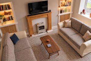 A cozy living room with a fireplace, sofas, a coffee table, and a bookshelf.