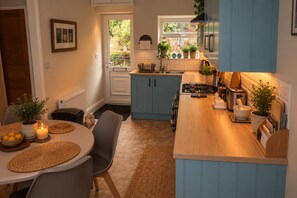 A compact kitchen with a dining area, featuring a stove, sink, and various appliances.