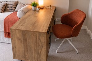 A wooden desk with a chair, a plant, and a lamp.