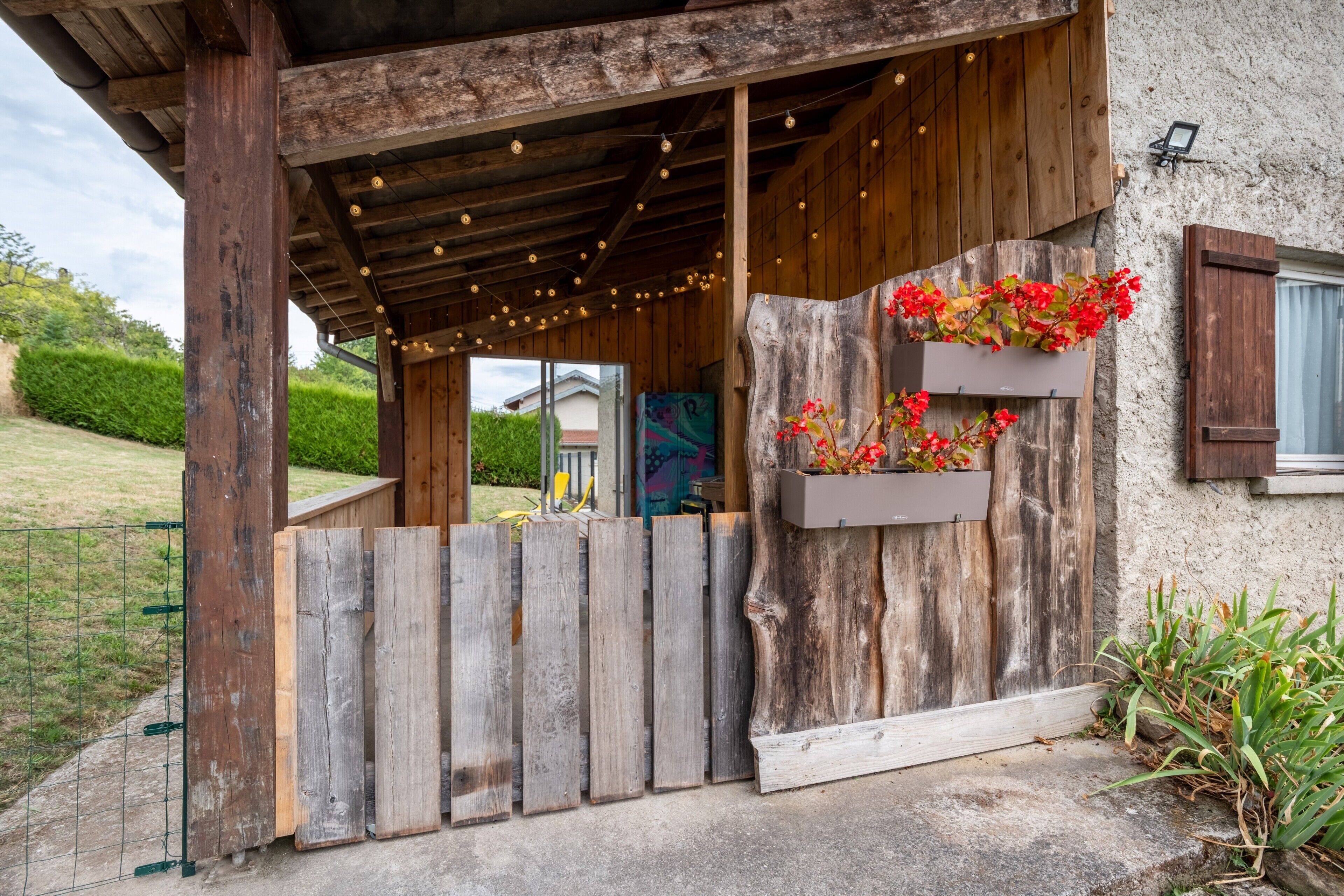 Une structure rustique en bois, dotée d’un porche couvert, d’une clôture en bois et de jardinières.