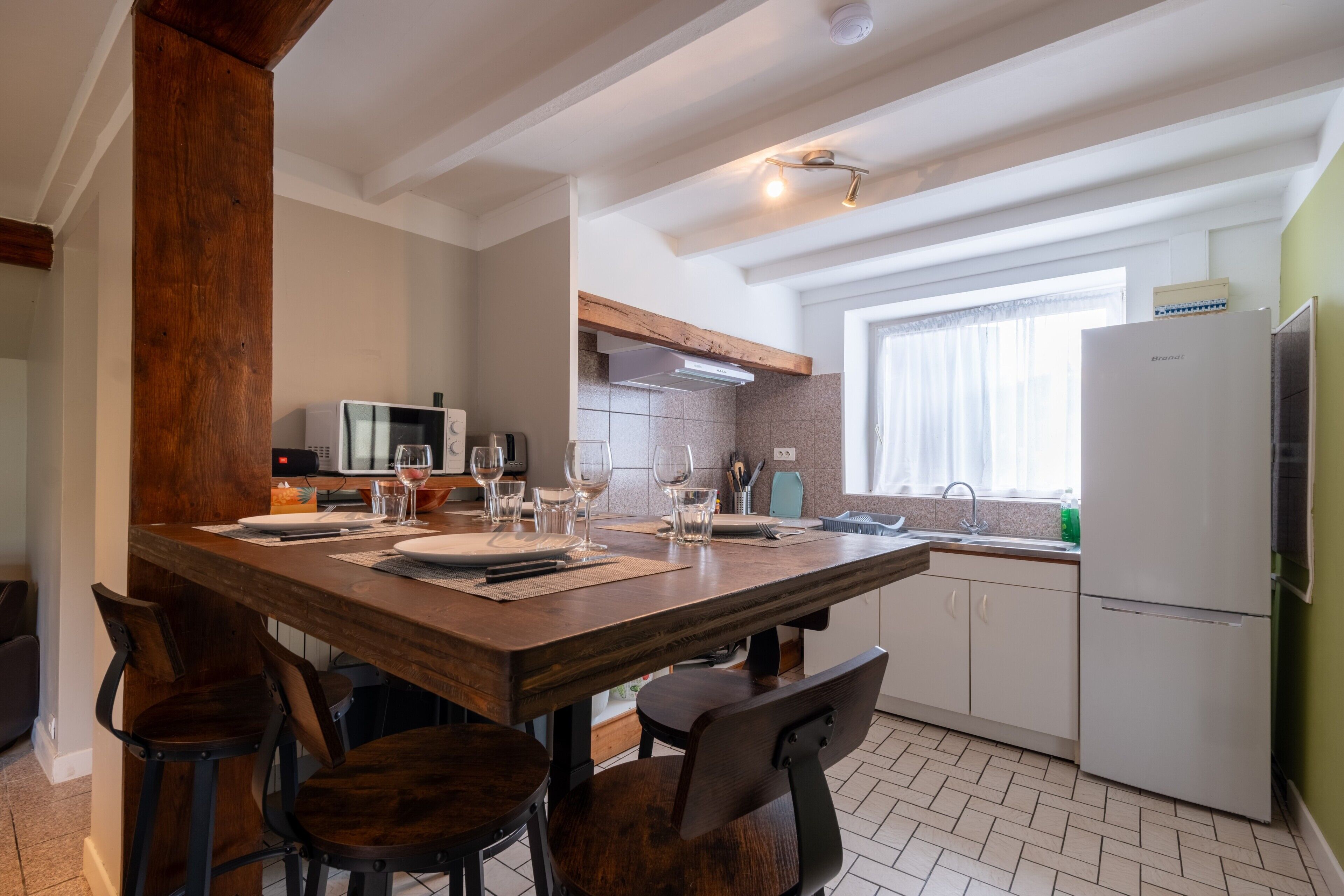 Una cocina moderna con una mesa de comedor de madera, taburetes de bar y un horno empotrado.