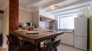 Una cocina moderna con una mesa de comedor de madera, taburetes de bar y un horno empotrado.