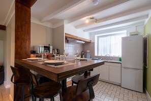 Una cocina moderna con una mesa de comedor de madera, taburetes de bar y un horno empotrado.