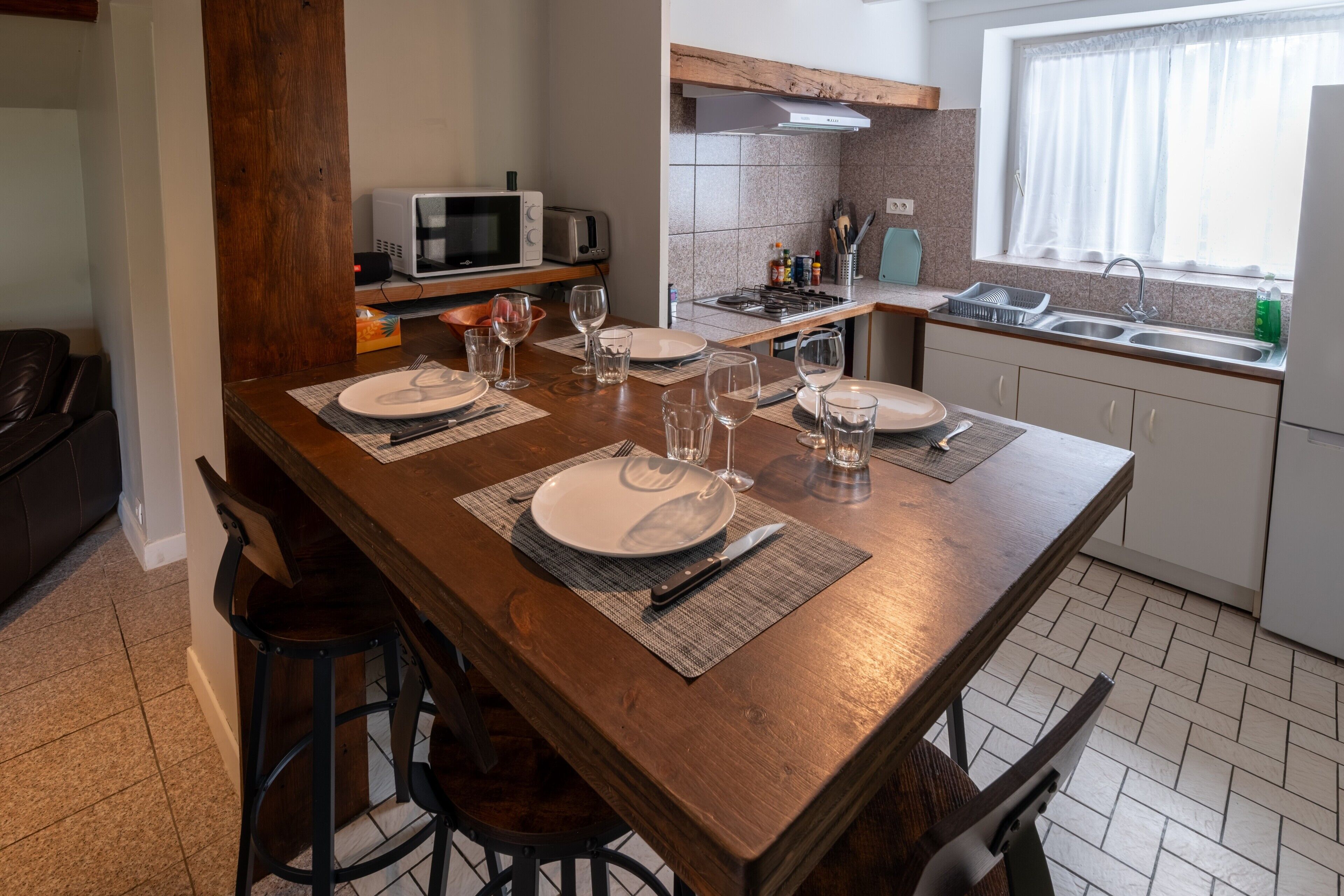 Un comedor con mesa de madera dispuesta para cuatro, una cocina con estufa a gas y un ventanal con vistas.