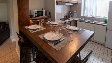 Un comedor con mesa de madera dispuesta para cuatro, una cocina con estufa a gas y un ventanal con vistas.
