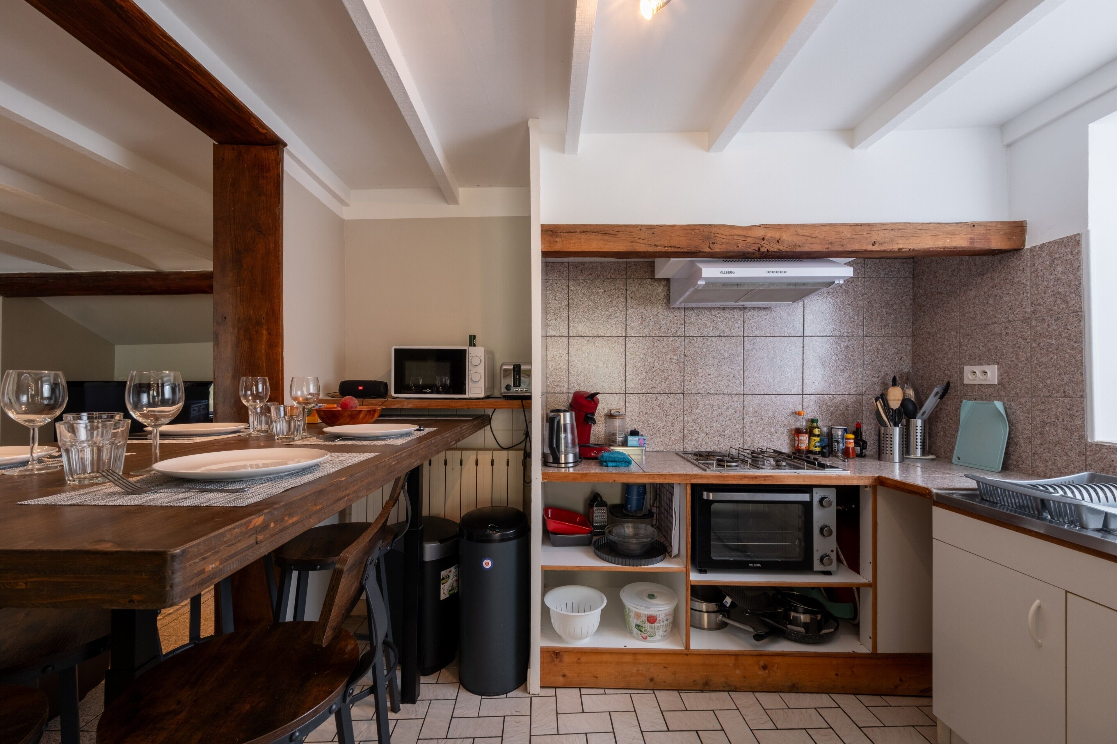 A compact kitchen with a dining area, equipped with a microwave, toaster, and stove.