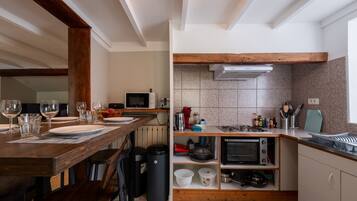 A compact kitchen with a dining area, equipped with a microwave, toaster, and stove.