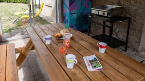 Un tavolo da picnic in legno con una bottiglia di succo, un bicchiere e una rivista.