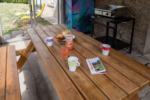A wooden picnic table with a bottle of juice, a glass, and a magazine.