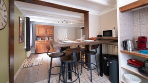 Una cucina con isola centrale, sgabelli da bar, forno a microonde e macchina da caffè.