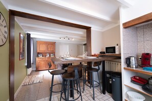 A kitchen with a central island, bar stools, a microwave, and a coffee maker.