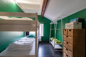 Una habitación pequeña y funcional con literas, un tendedero y un espacio de almacenamiento.