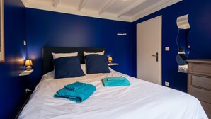 Una camera d'albergo con un letto, un comodino, una lampada, uno specchio e una porta.