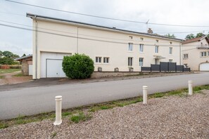 A two-story building with a garage, a small garden, and a paved driveway.