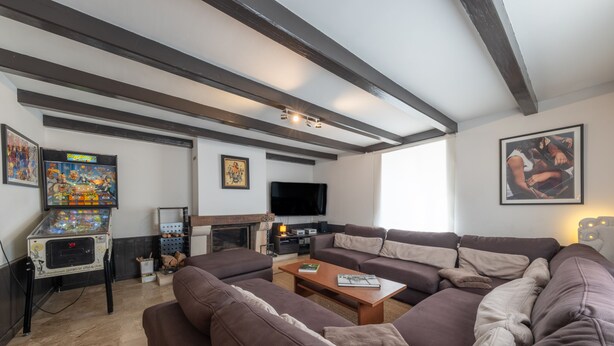 A living room with a large sectional sofa, a fireplace, a flat-screen TV, and a pinball machine. - La Grande Escapade Holiday Home – 6 Guests (Up to 10 on Request), Countryside View, Terrace, Wi-Fi (Xertigny)
