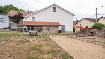 A residential area with a house, a tennis court, and a barbecue setup.