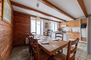 A wooden interior with a dining table set for six, kitchen cabinets, and a refrigerator.