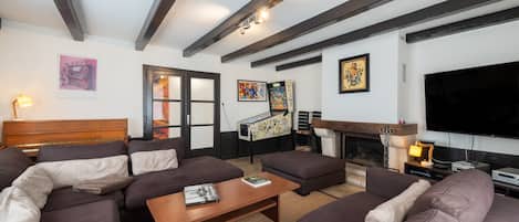 A living room with a large sectional sofa, a coffee table, a fireplace, a television, and a piano.
