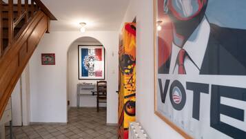 Un pasillo con una escalera de madera, un radiador y un cartel grande con la palabra 'VOTE'.