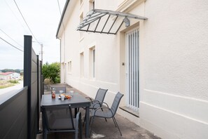 An outdoor dining area with a table and chairs, a bottle of juice, and a glass of orange juice.