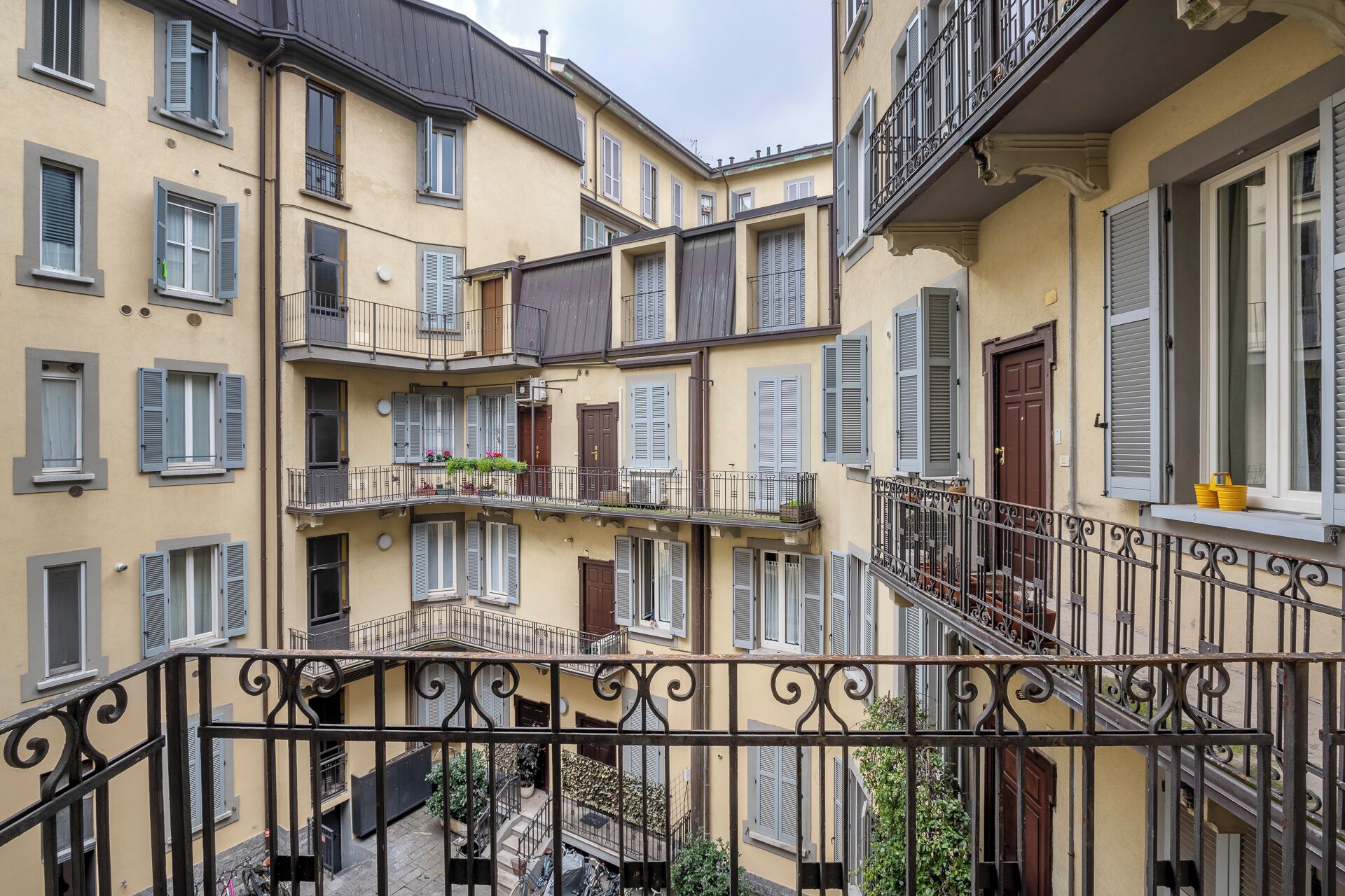 A multi-story building with balconies, a wrought iron railing, and a staircase.