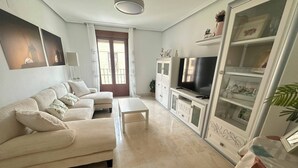 A living room with a sofa, a coffee table, a TV, and a cabinet with glass doors.