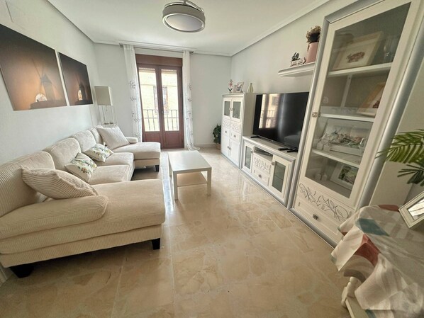 A living room with a sofa, a coffee table, a TV, and a cabinet with glass doors.