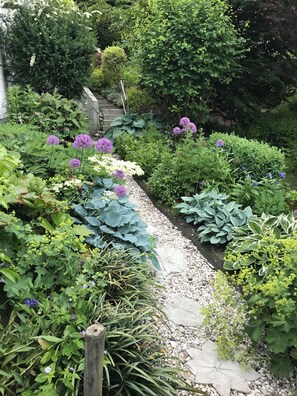 Ein Garten mit Kiesweg, verschiedenen Pflanzen und einem Holzpfosten.