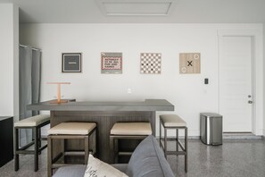 A modern kitchen with a bar area, a seating arrangement with stools, and a trash bin. - A/C Game room, Golf Cart,  Autism Friendly (Port St Joe)