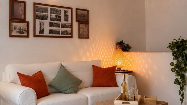 A living room with a white sofa, a wooden coffee table, and a lamp. There are framed pictures on the wall. - Just a short walk from the Cathedral, the Swabian Castle, the harbor, and downtown. (Trani)