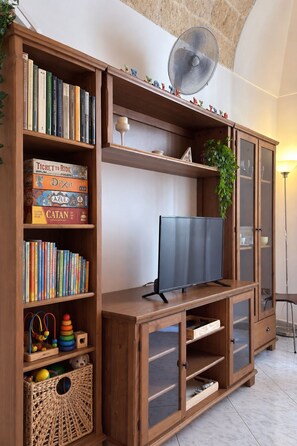 Ein Holzunterhaltungsschrank mit einem Flachbildfernseher, Regalen für Bücher und Spiele sowie einem dekorativen Ventilator.
