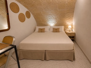 Ein Schlafzimmer mit einem Bett, einem Nachttisch, einer Lampe, einem Sessel und einem Tisch.