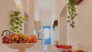 A dining area with a large pizza on a wooden board, a fruit bowl, and a plant on a shelf. - Just a short walk from the Cathedral, the Swabian Castle, the harbor, and downtown. (Trani)