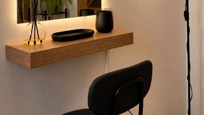 A modern room with a wooden desk, a black chair, a floor lamp, and a mirror reflecting a door and a plant. - Just a short walk from the Cathedral, the Swabian Castle, the harbor, and downtown. (Trani)