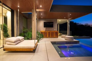 A modern outdoor living area with a pool, seating, and a wooden structure. - Oceanview Luxury Home in Pacifico Coastal Living (Coco)