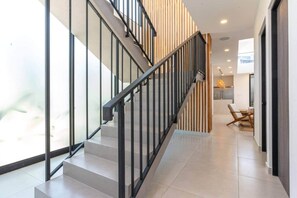 A modern staircase with glass railings and a minimalist design. - Oceanview Luxury Home in Pacifico Coastal Living (Coco)